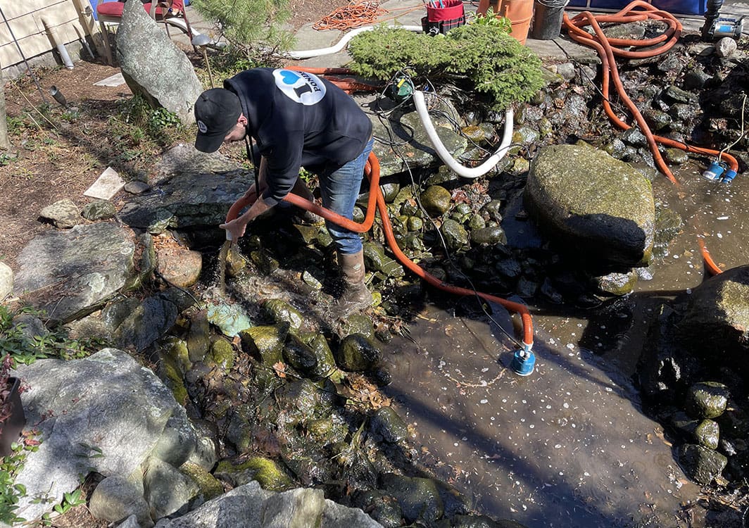 Technician servicing a pond pump and plumbing lines