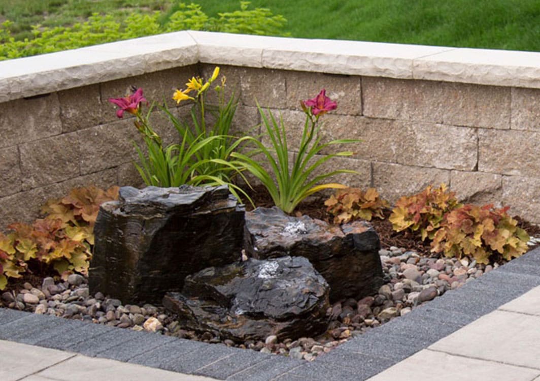 Stacked slate fountain in a landscaped bed