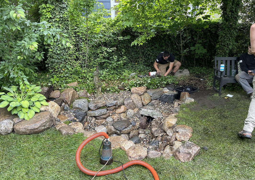 Repairing settled stonework along a pond edge