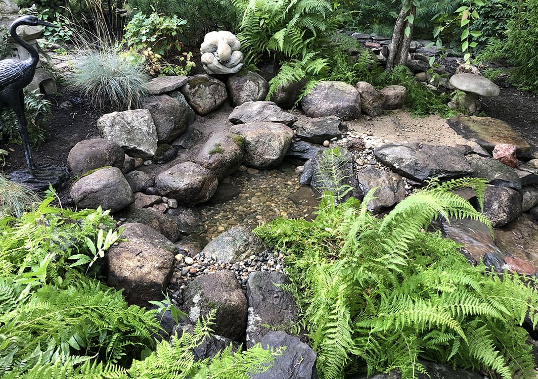 Compact pondless waterfall beside a patio seating area