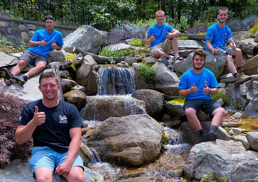 NEAL construction crew posing on the rockwork of a waterfall they built