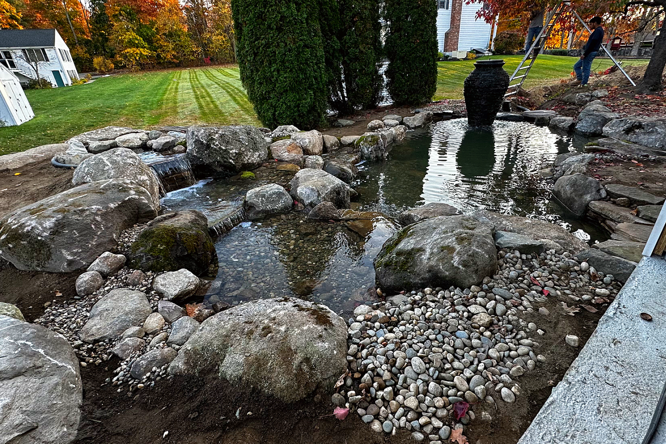 Backyard pond with rocks and waterfall feature.