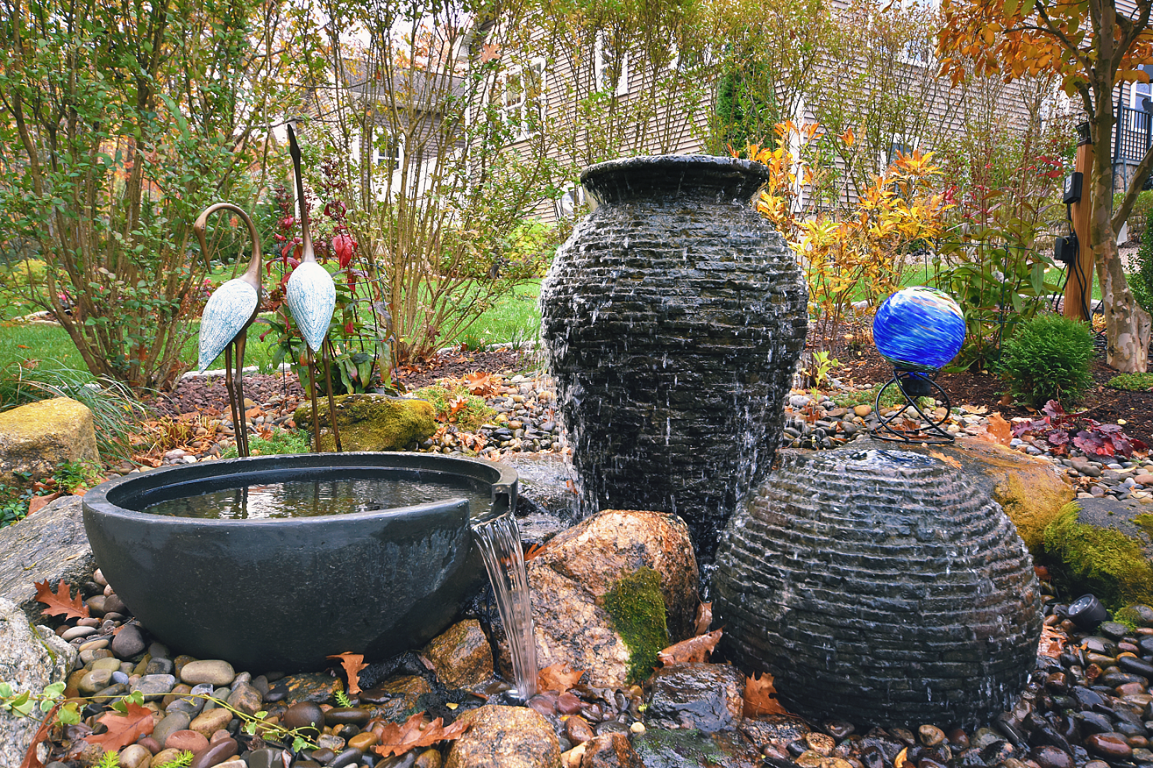 Garden fountains with sculptures and colorful glass orb.